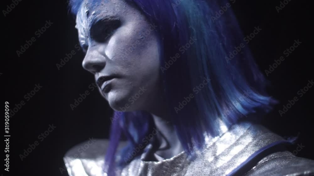 Close up, alien with blue hair is standing and looking somewhere Close up, alien with blue hair is standing and looking somewhere