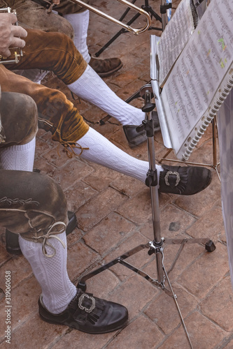 piernas de hombre con vestimenta de músico tradicional, y atril con partituras musicales 