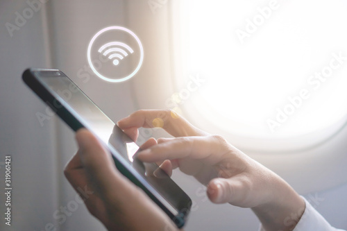 Woman hand using smartphone with wifi icon in airplane background. photo