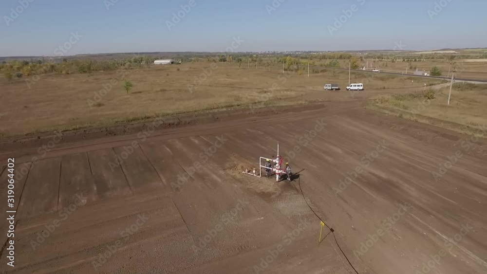 oilmen are inspecting and checking oil well in field, aerial view oilmen are inspecting and checking oil well in field, aerial view