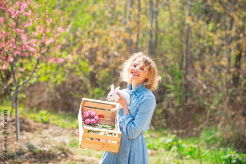 Funny girl hold rabbit on green field background. Pretty girl preparing for Easter. © Volodymyr