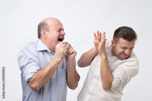 Sick bald caucasian man holding napkin or tissue, trying to cover mouth while sneezing