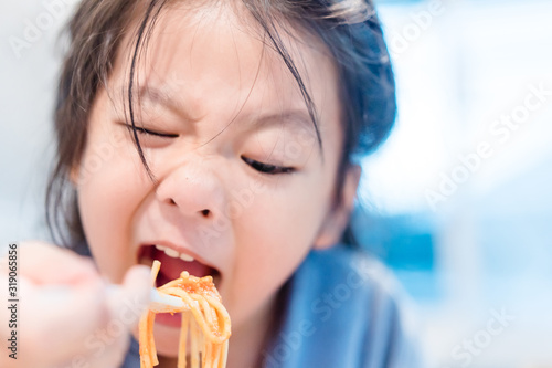 Hungry face and enjoy eating concept.Little asian girl enjoy eating with spaghetti bolognese with cheese on a plate in lunch time at restaurant.