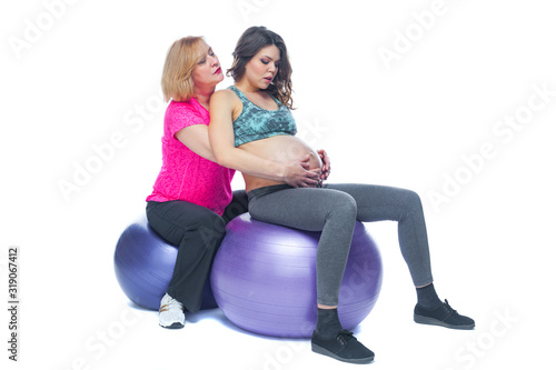Young pregnant woman exercising with physiotherapist in birthing school. Doctor's help conceptat in antenatal class. Isolated white background.
