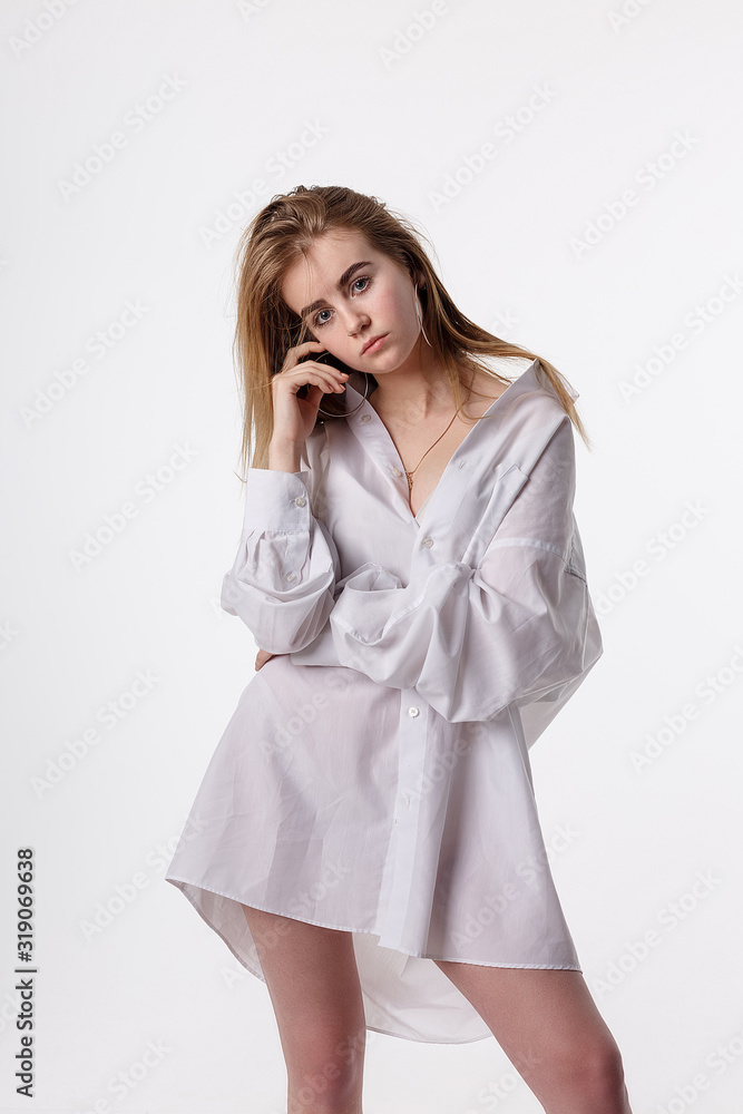 young thin pretty female wearing shirt posing in studio with bare feet. attractive cute teenage girl with long hair isolated on white background. model tests of skinny caucasian woman, studio portrait young thin pretty female wearing shirt posing in studio with bare feet. attractive cute teenage girl with long hair isolated on white background. model tests of skinny caucasian woman, studio portrait