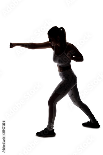 Valokuva Fit young woman in a fighting stance wearing athletic sports wear and exercising by punching or practicing self defense