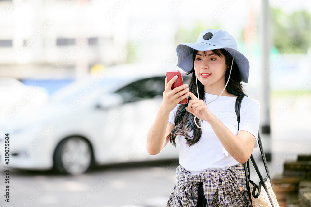 Young pretty woman using smartphone while walking in city, using mobile application for Shuttle service.