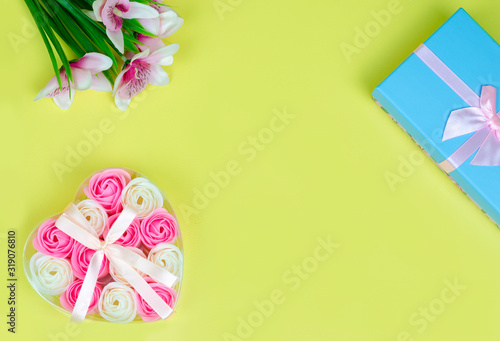 A gift for a woman on March 8, Valentine's Day or another holiday. Blue gift box with a pink bow. Heart of pink and white roses on light green background