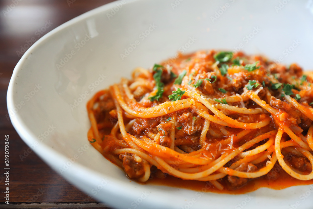 spaghetti Bolognese with minced beef and tomato sauce garnished with parmesan cheese and basil , Italian food