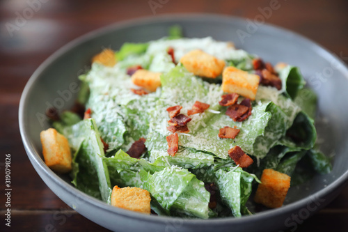 Caesar salad with crispy bread and bacon close up on wood background