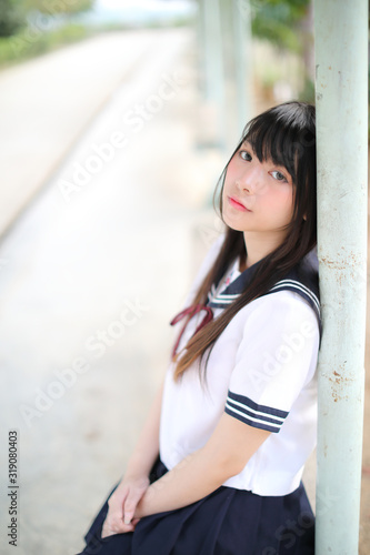 Asian school girl sitting with outdoor background