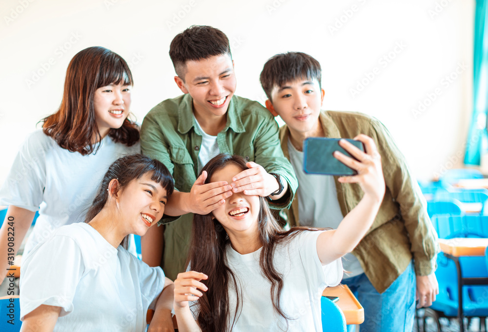 happy young group of teenagers making fun selfie in classroom
