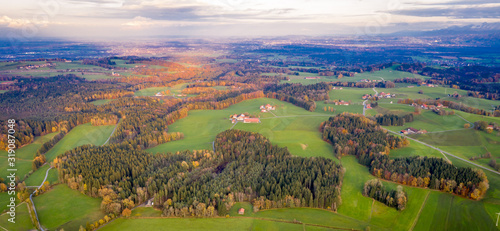 Aerial view Autumn landscape in Bavaria near Miesbach. Road going into the distance and the peaks of the Alps on the horizon. Clouds sky, Yellow trees and green field