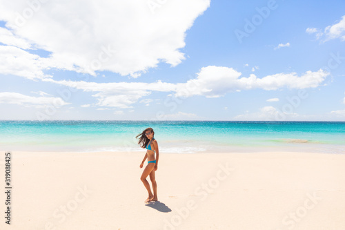 Beach vacation paradise Hawaii tourist woman walking on white sand wide perfect beach summer holiday in the Caribbean.