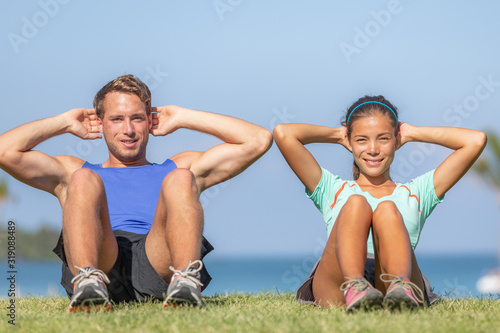 Situps fitness people training abs sit-up outdoor in grass park. Happy fit athletes couple.