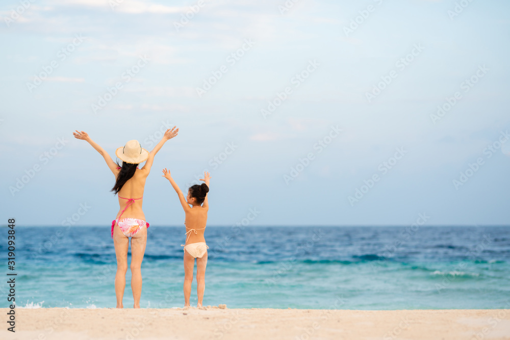 ビーチで両手を上げる母と娘