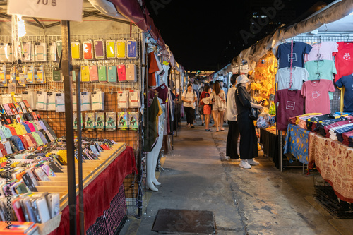 Tourist and locals walking and shopping at Rachada Night train market (Talad Rot Fai). market with plenty of shops with colorful canvas roofs at night in Bangkok, Thailand