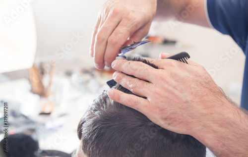 Barber making stylish haircut with in beauty salon.