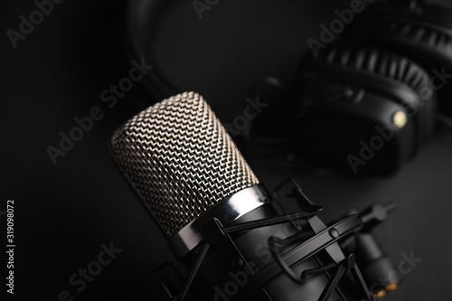 Microphone for podcasts and studio headphones on a black background, horizontal frame