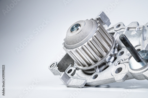 New metal automobile pump for cooling the engine of a water pump on a gray background. The concept of new spare parts for the car engine