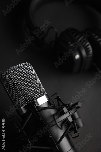 Microphone for podcasts and studio headphones on a black background, vertical frame