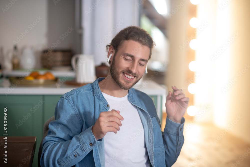Naklejka premium Smiling man enjoying his favourite song in wireless earphones