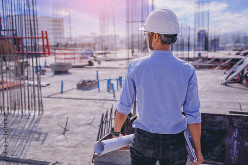 Smart civil architect engineer inspecting and working outdoors building side with smart pad and blueprints. engineering and architecture concept.