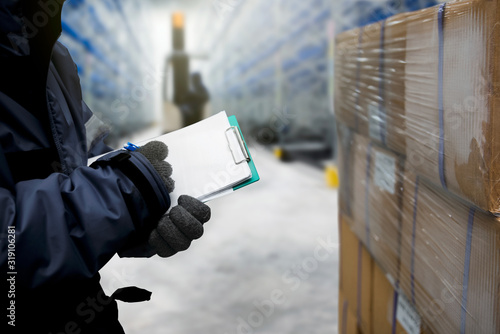 Fotografie Closeup shooting hand of worker with clipboard checking goods in freezing room o