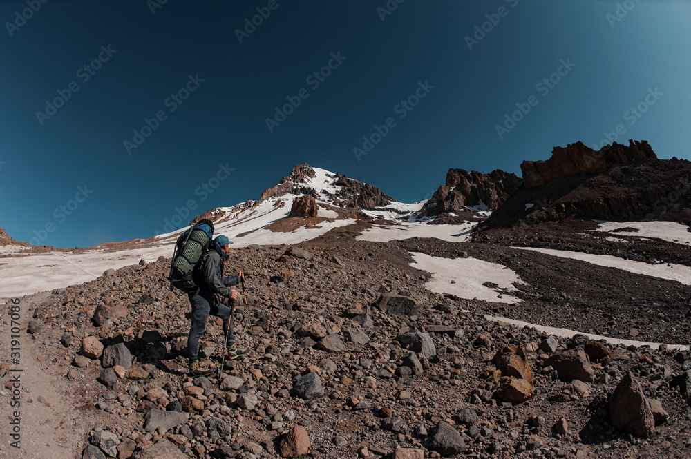 Man standing on the rocky path looking up to the mountain