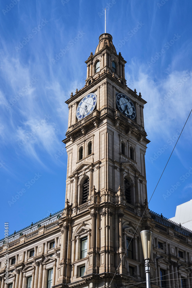 Historic Victorian style clock tower in Melbourne CBD with blue sky and white clouds