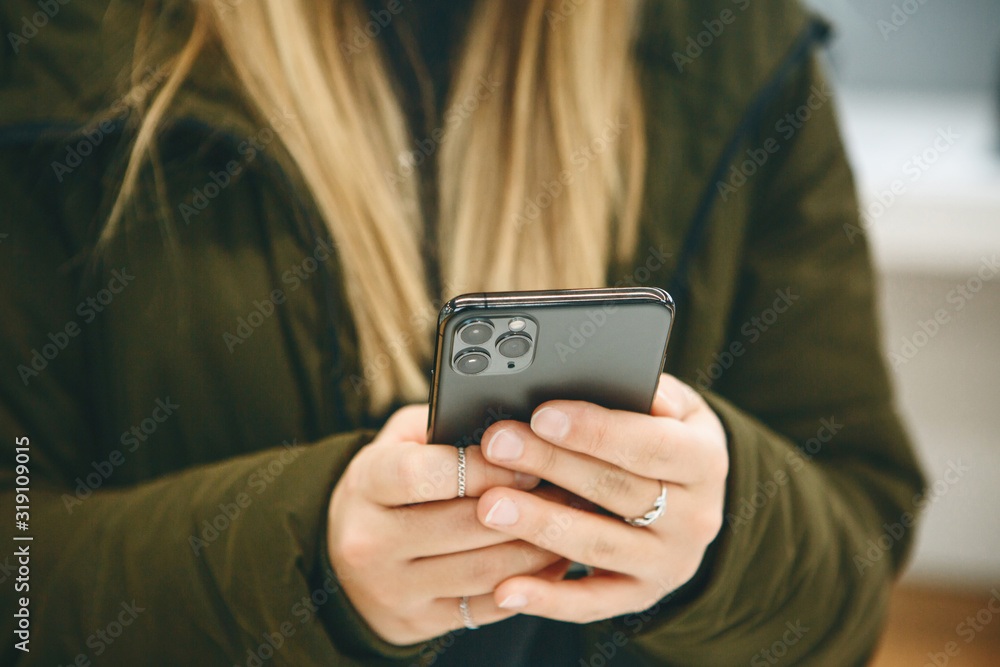 The girl uses a new cell phone with a triple camera. The girl uses a new cell phone with a triple camera.