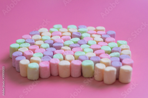 Colorful marshmallows on pink background  macro. Fluffy marshmallows texture close up in pastel colors