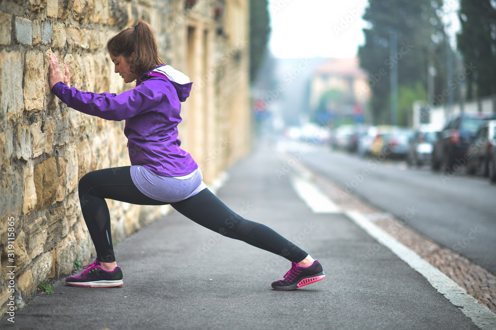 Young girl practices stretching in the city on a wall of a building Young girl practices stretching in the city on a wall of a building
