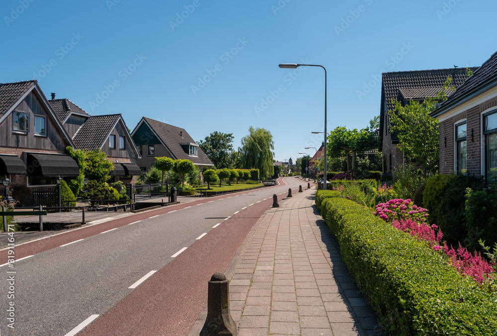 Cozy cottages located in quiet dutch town in Netherlands. Summer landscape with houses on a green street.
