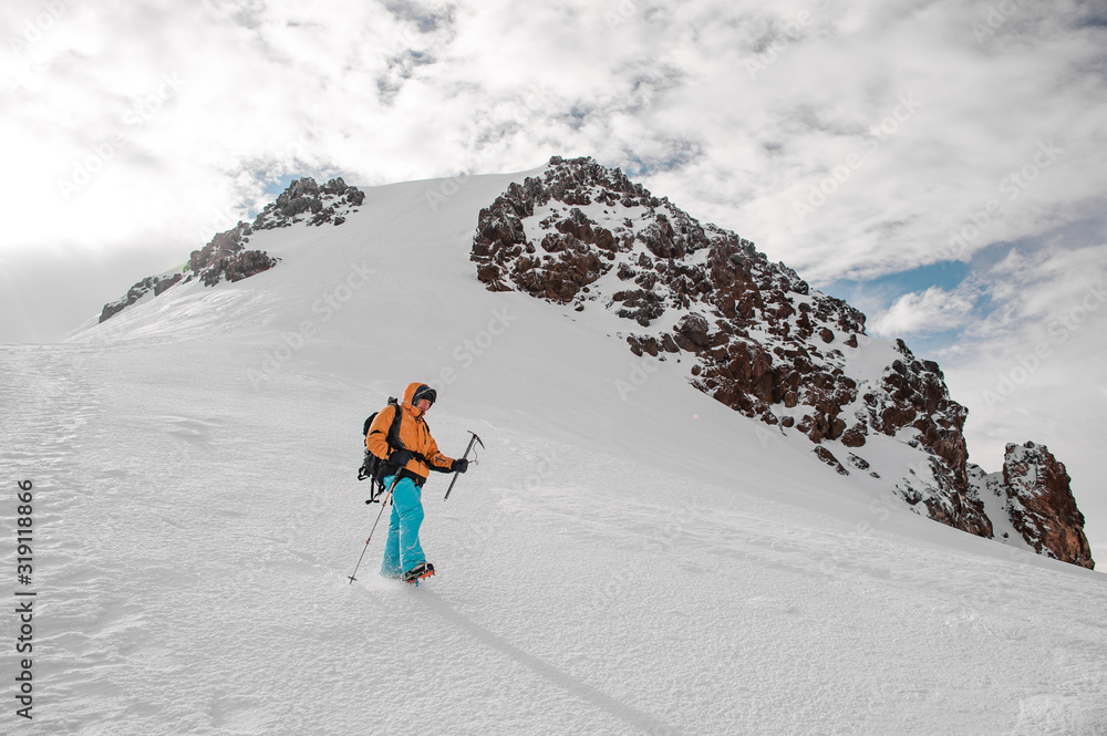 Guy with hiking equipment standing on the snow on the mountain hill