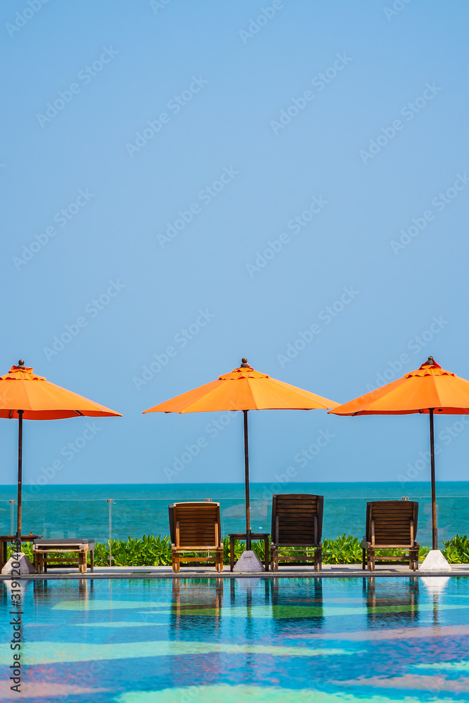 Umbrella and chair around outdoor swimming pool neary sea in hotel resort