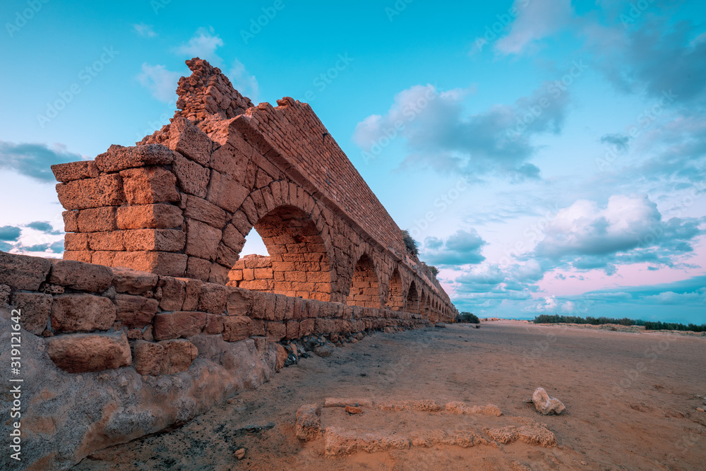 Aqueduct in ancient city Caesarea at sunset. Creative color