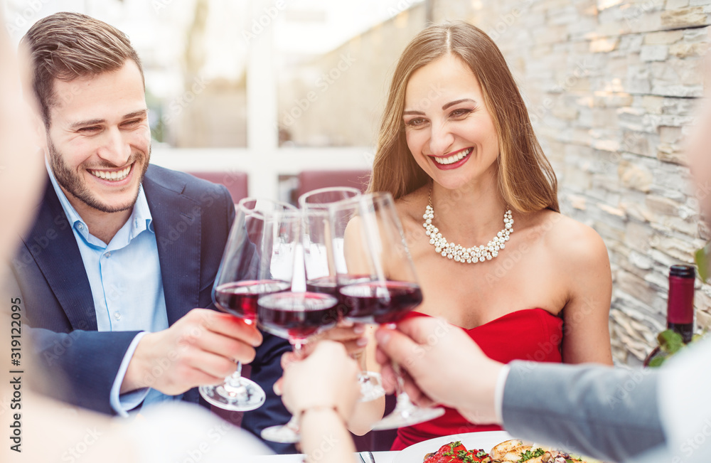 People sitting on restaurant table toasting with red wine
