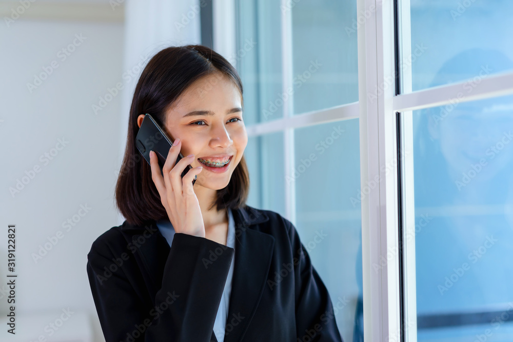 Smiling Asian woman talking smartphone in the office. Smiling Asian woman talking smartphone in the office.
