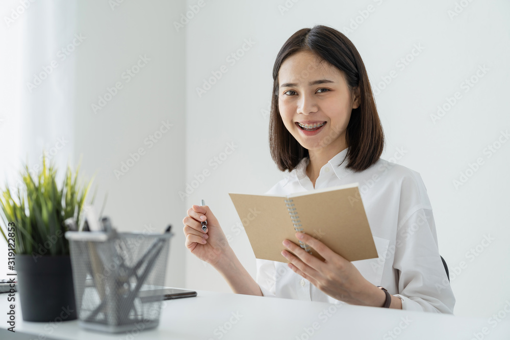 Woman holding blank notebook and pen on table in office. Woman holding blank notebook and pen on table in office.