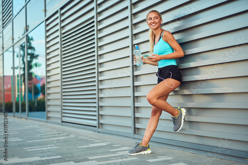 Modern sportswoman making pause after jogging in the urban area.