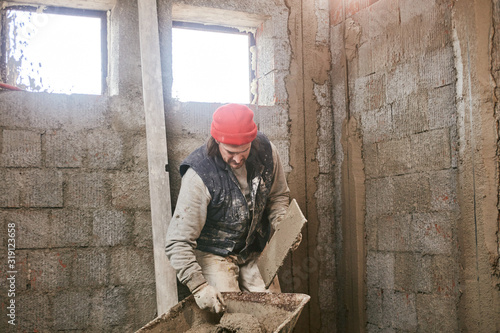 Real construction worker making a wall inside the new house.
