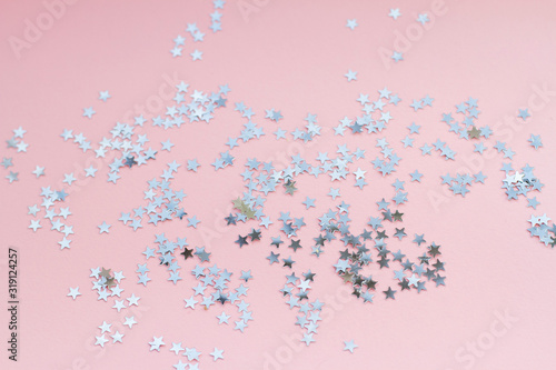 Silver stars shine on a bright pink background. Festive holiday bright background.