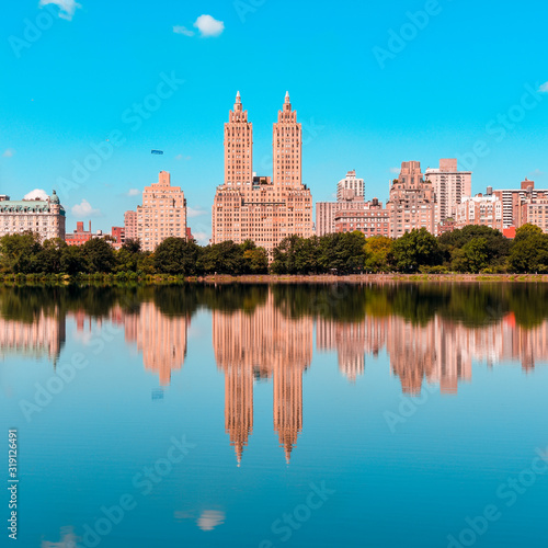 Photo REFLECTION OF BUILDINGS IN LAKE AGAINST BLUE SKY
