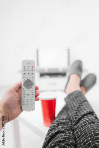 Man drinking soda juice and looking at TV with legs on the table in living room. photo