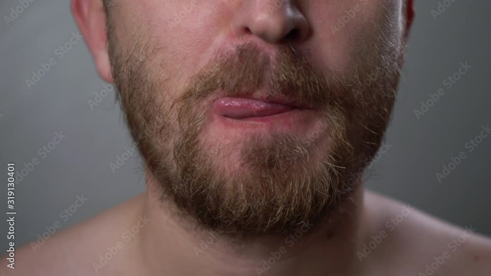 A young man touches his big beard and mustache with his hand, close-up. A man is preparing to shave facial hair. Hair removal in front of a mirror. Men's care. Change of image. A young man touches his big beard and mustache with his hand, close-up. A man is preparing to shave facial hair. Hair removal in front of a mirror. Men's care. Change of image.