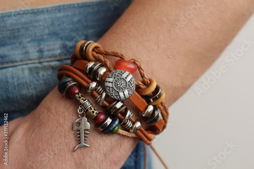 Men's ethnic bracelet on the arm The man's hand is wearing a bracelet in the of jeans photo