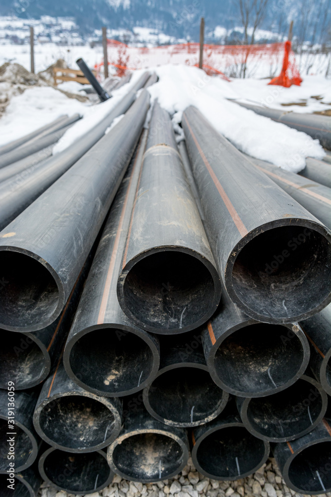 Pile of plastic pipes on construction site ready to be used.