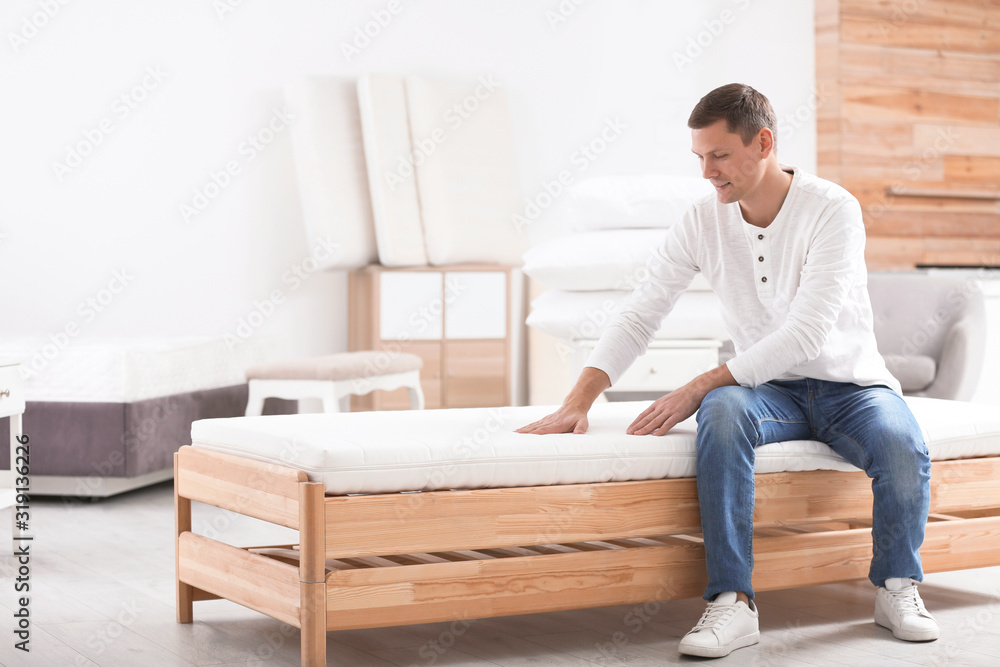 Man touching mattress in furniture store. Space for text Man touching mattress in furniture store. Space for text