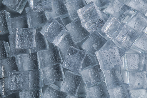 Crystal clear ice cubes with water drops as background, top view